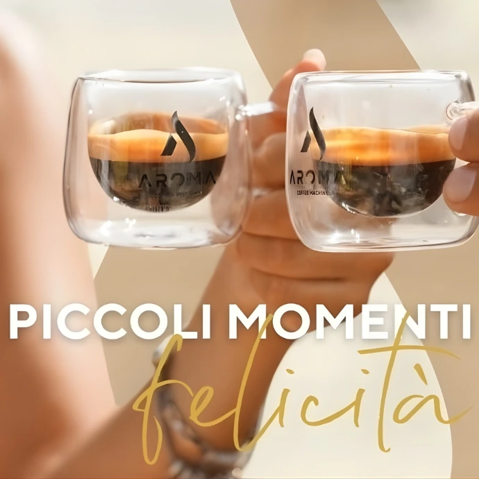 Ruke koje drže dvije šoljice espresso kafe sa Aroma logom