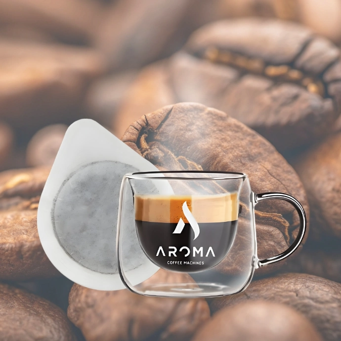 Šoljica sa logom Aroma brenda i espresso padom pored nje, sa kafe pozadinom