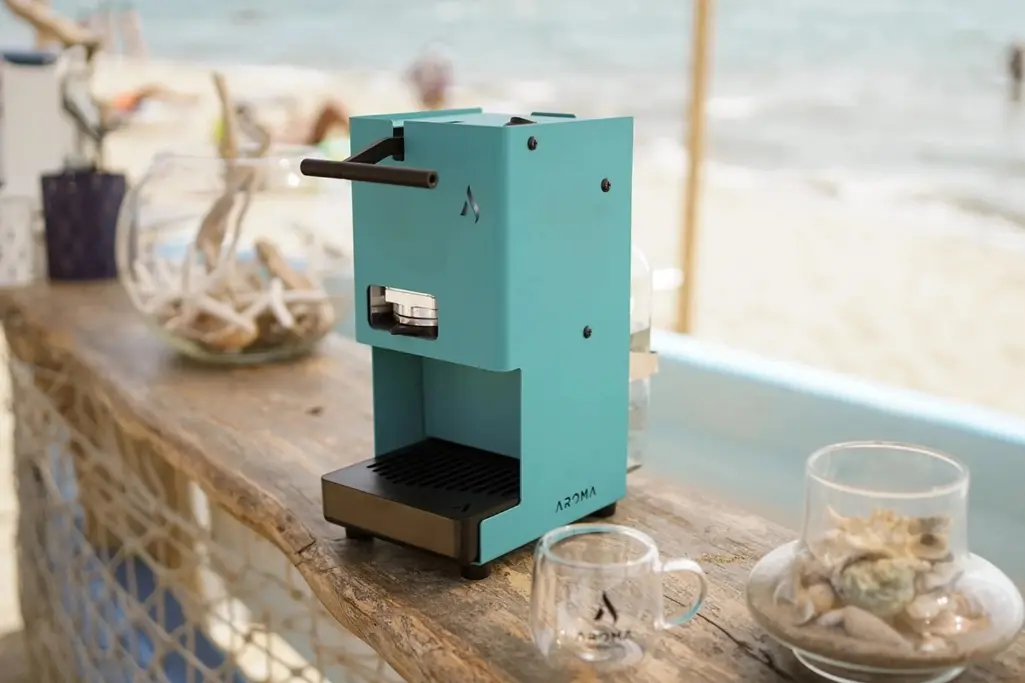 Aroma E.GO aparat, tirkizne boje, na stolu na plaži
